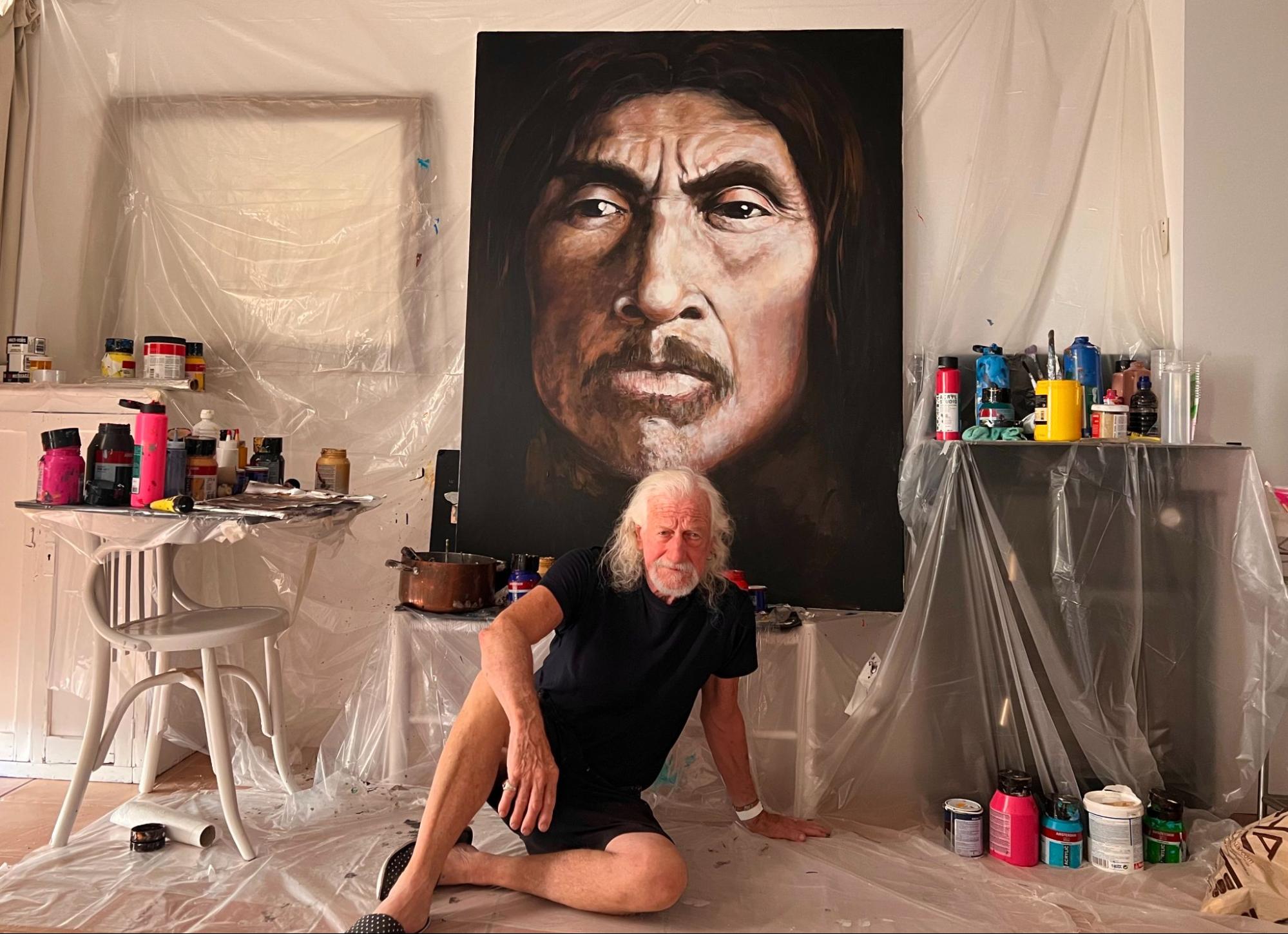 Paul Ygartua in his studio beneath a large portrait painting